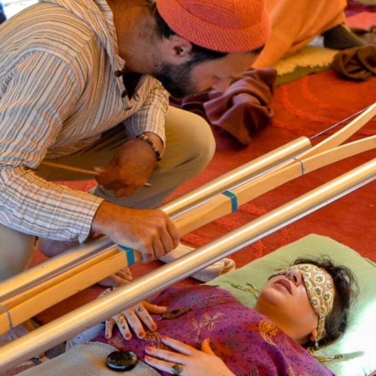 Yoav holding chimes above a blindfolded participant during a guided sound healing session.