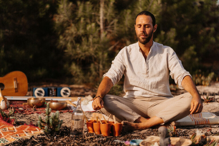 Man meditating cross-legged in nature during a sound healing practice in Portugal.