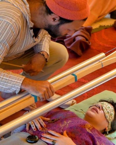 AD677426-47CA-4ACB-9473-D444485E104E Yoav holding chimes above a blindfolded participant during a guided sound healing session.