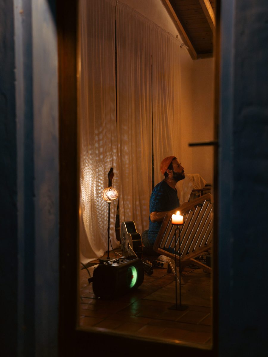 DSC00486-Verbeterd-NR A distant view of Yoav singing surrounded by sound healing instruments in a room bathed in candlelight.